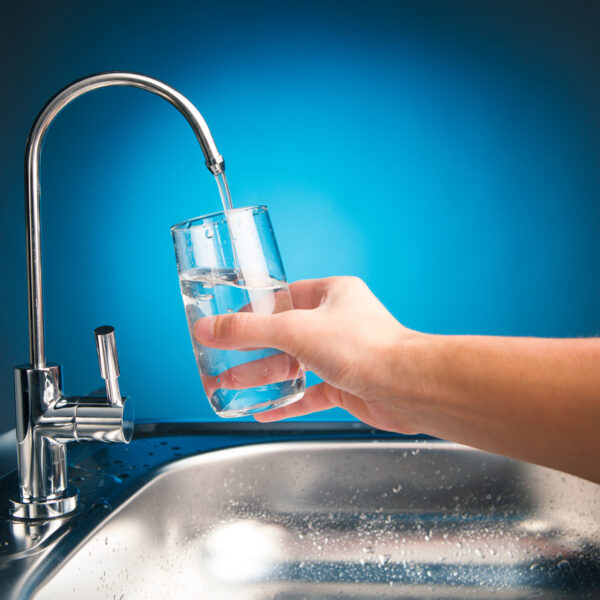 hand pouring a glass of water from filter tap hand pouring a glass of water from filter tap, blue background